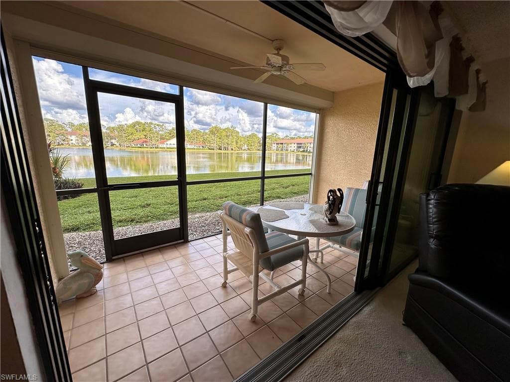 Sunroom / solarium featuring a ceiling fan, tile patterned flooring, a and a water view