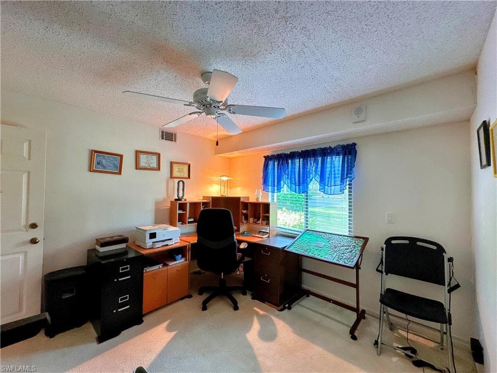 Office featuring a textured ceiling, light carpet, and a ceiling fan