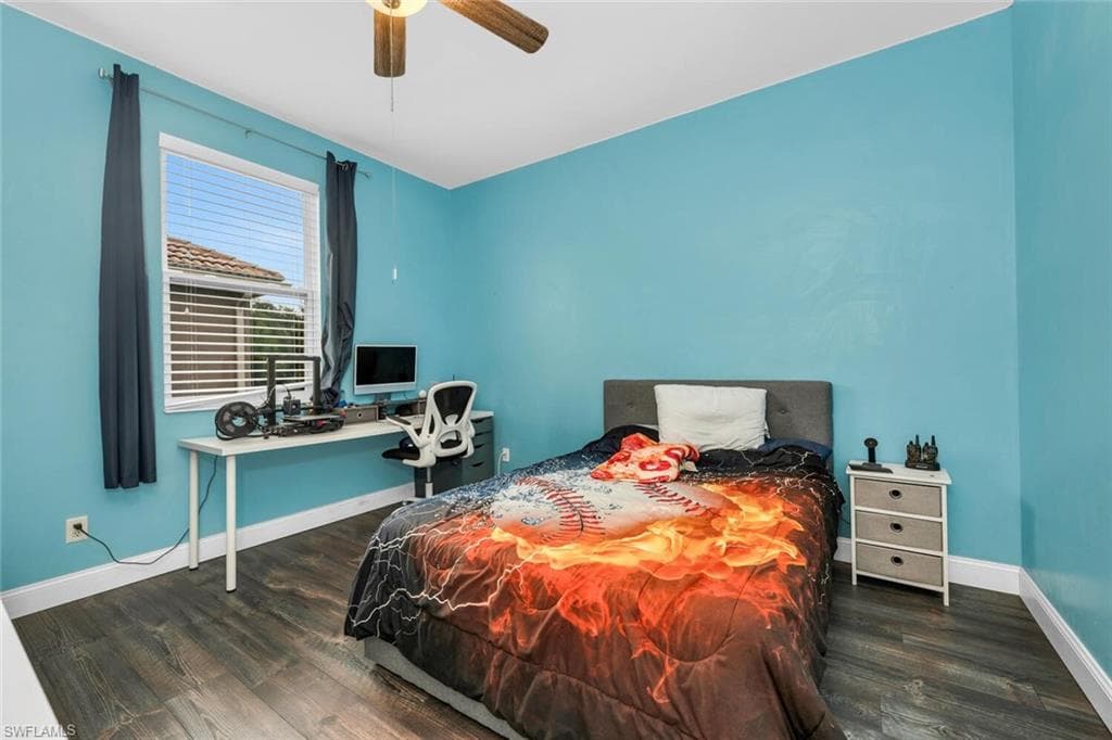 Bedroom featuring dark wood-type flooring, a ceiling fan, and a desk