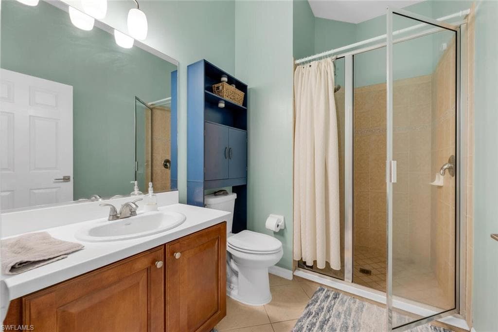 Bathroom with a shower stall, light tile patterned flooring, and vanity