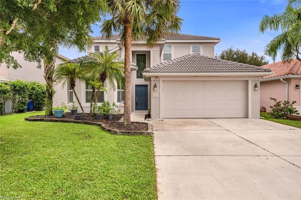 Mediterranean / spanish-style house with stucco siding, driveway, a front yard, a tile roof, and an attached garage
