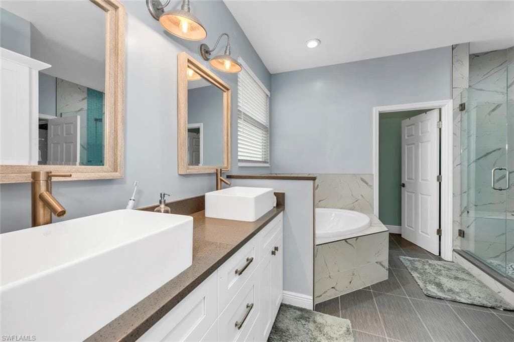 Full bath with a bath, a marble finish shower, double vanity, dark tile patterned floors, and recessed lighting