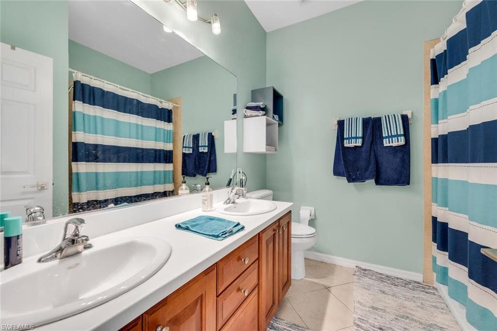 Full bath featuring light tile patterned floors, double vanity, and a shower with shower curtain