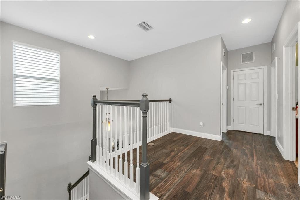 Hall with an upstairs landing, recessed lighting, and dark wood-style floors