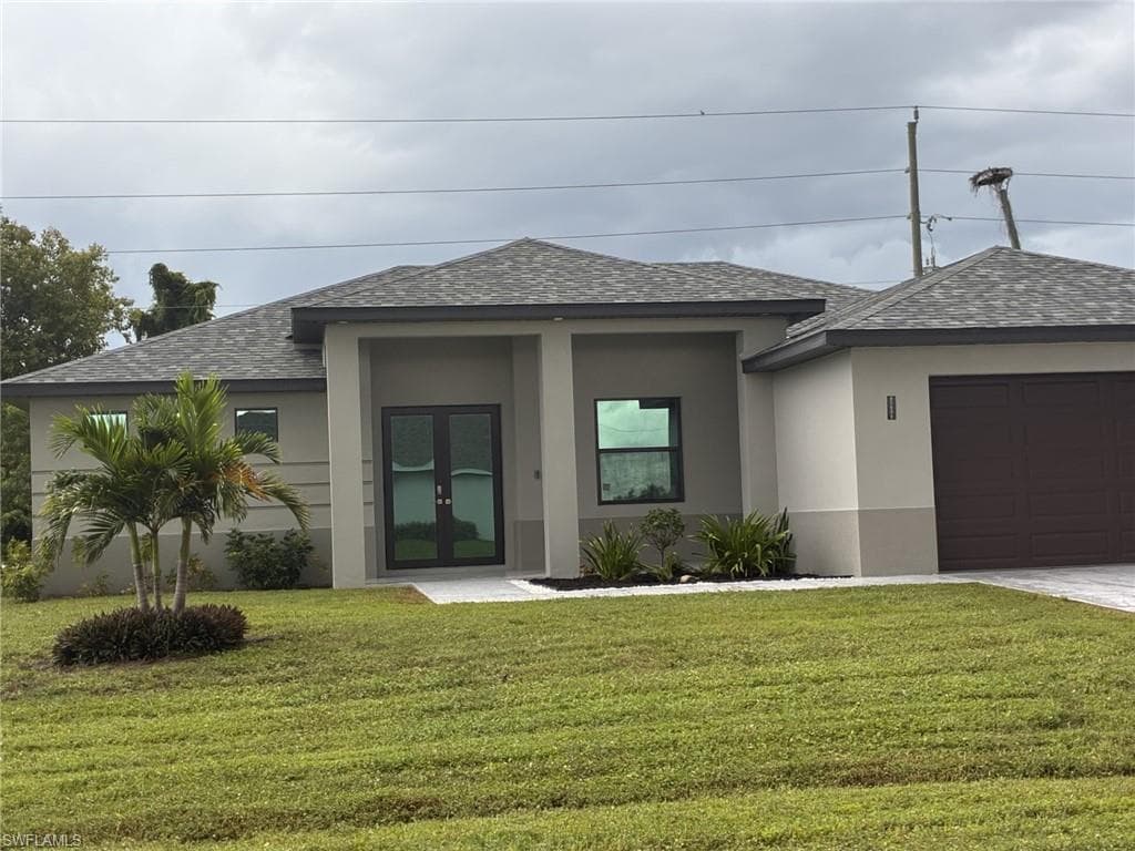 Contemporary-style home featuring roof with shingles, stucco block, a front yard, and an attached garage