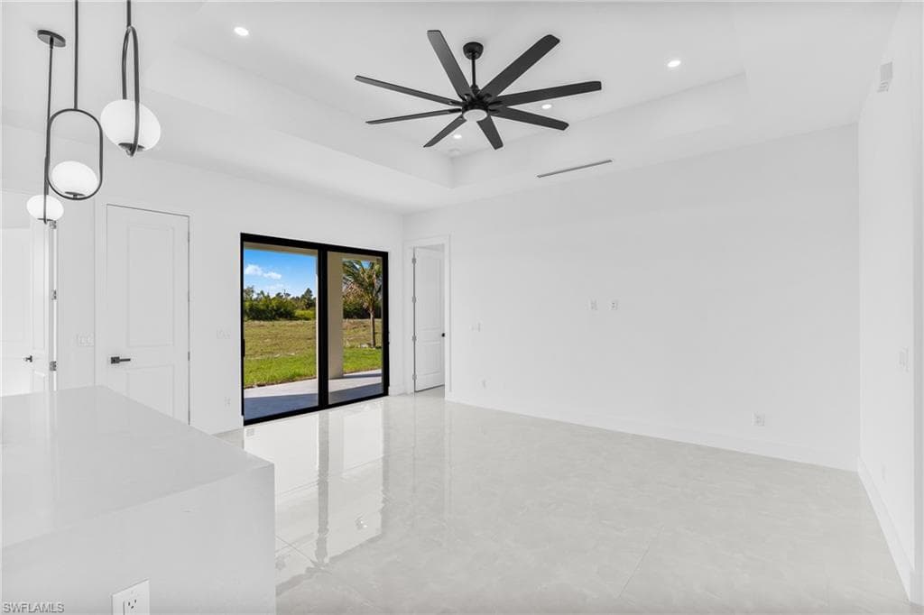 Unfurnished room featuring a tray ceiling, recessed lighting, and a ceiling fan