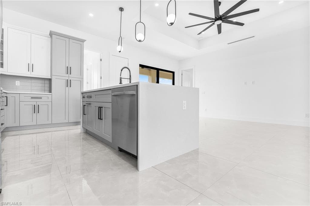 Kitchen featuring decorative light fixtures, gray cabinetry, a center island with sink, a ceiling fan, and dishwasher