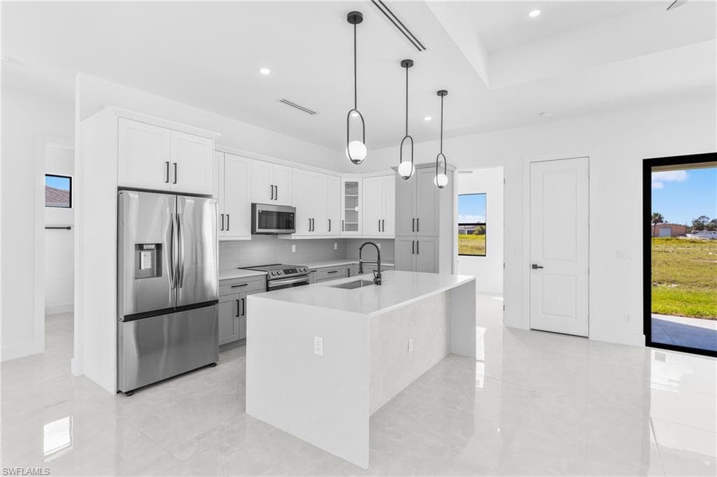 Kitchen featuring stainless steel appliances, glass insert cabinets, plenty of natural light, white cabinets, and recessed lighting