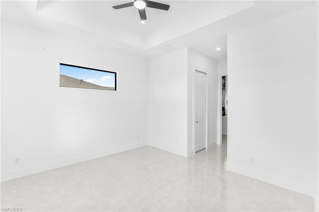 Empty room featuring a raised ceiling, ceiling fan, and recessed lighting