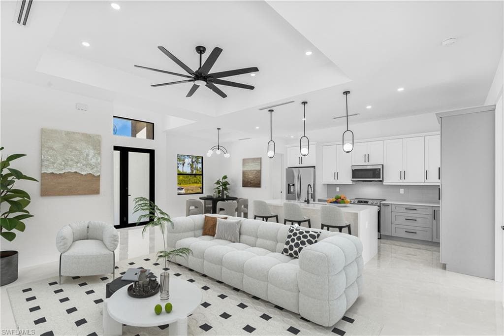 Living area featuring a raised ceiling, recessed lighting, and a ceiling fan