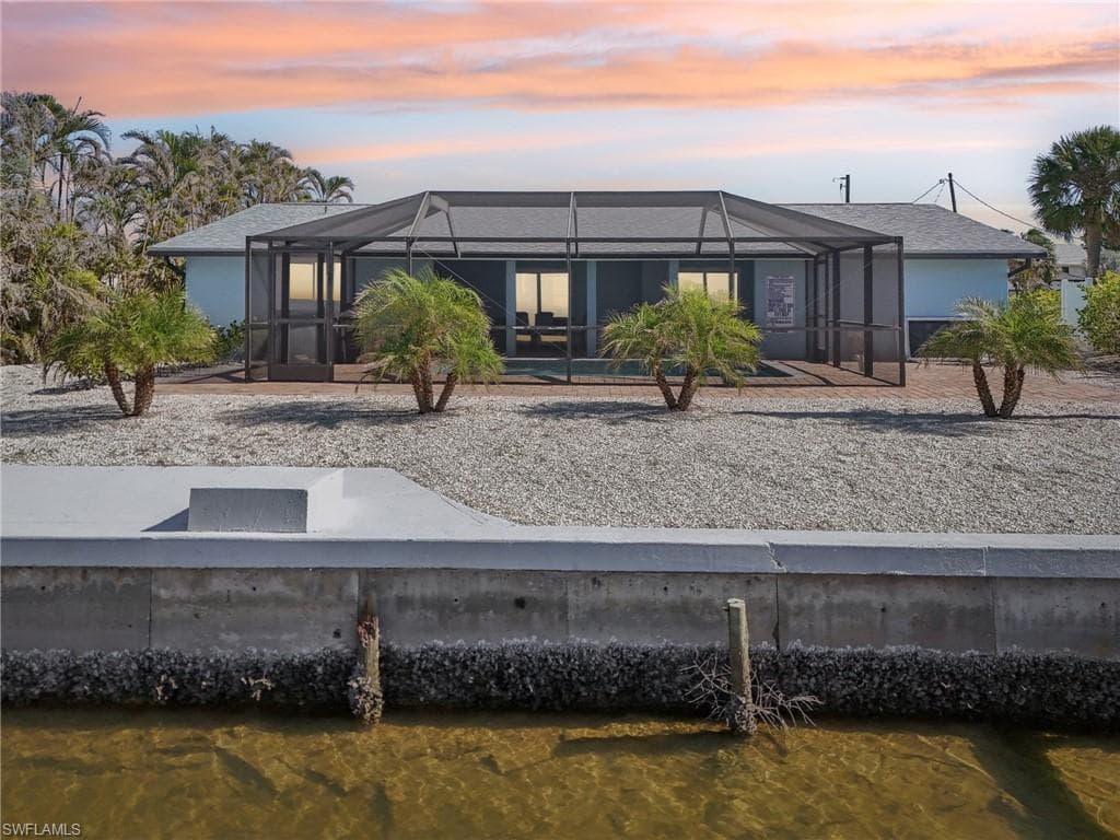 Back of house at dusk featuring a sunroom, a lanai, and stucco siding