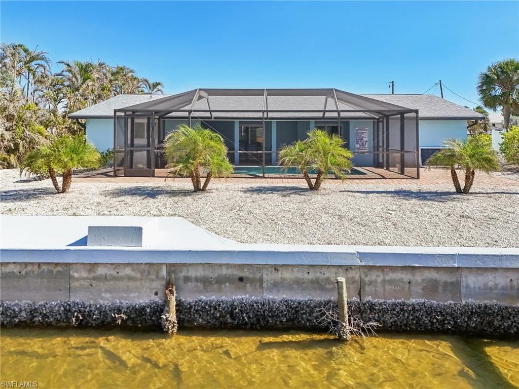 Rear view of property featuring a sunroom, a lanai, and a water view