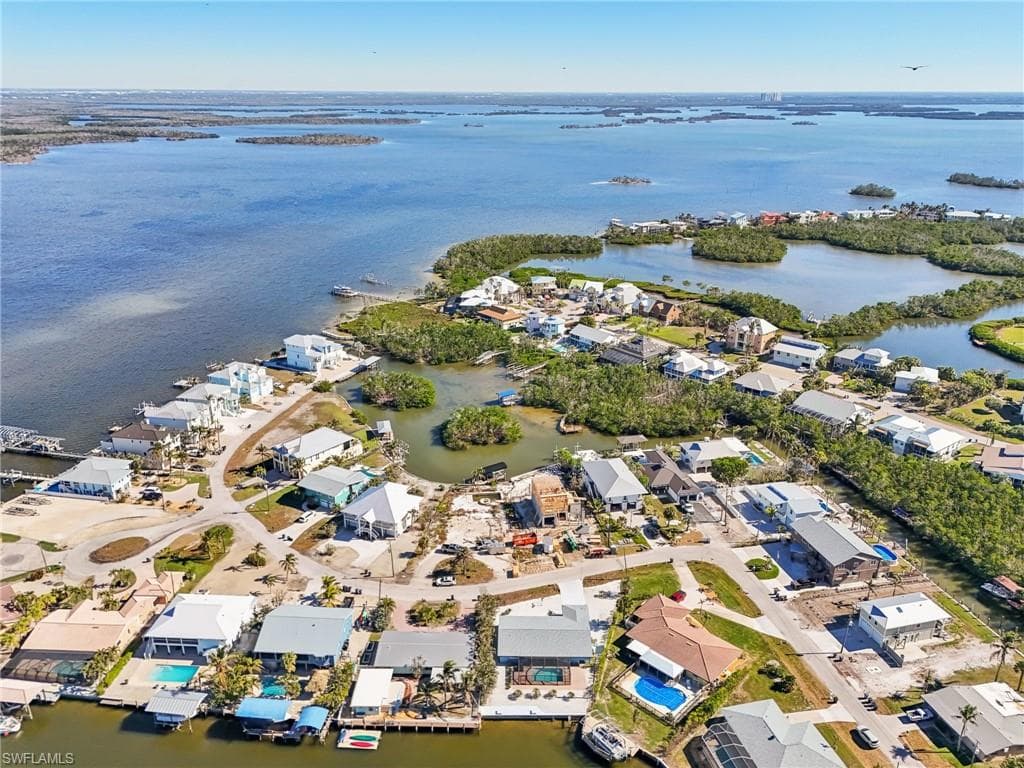 Aerial view of property and surrounding area featuring nearby suburban area and a nearby body of water