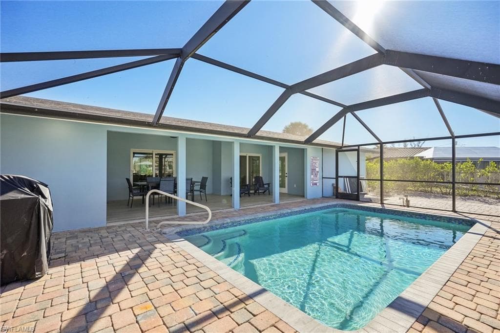 Swimming pool with a sunroom, glass enclosure, and a patio area