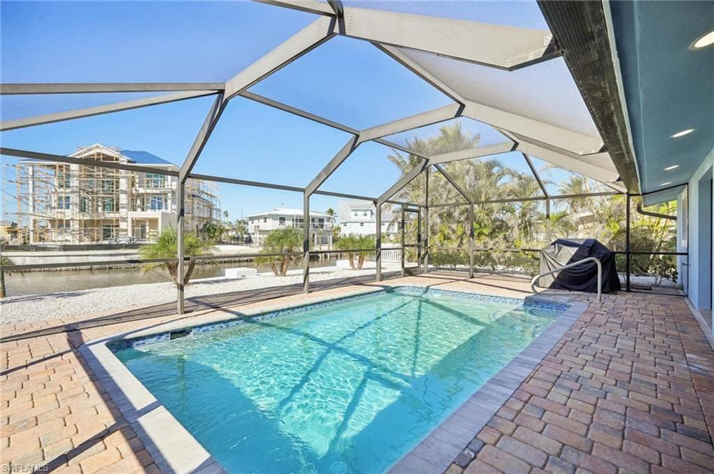 Swimming pool with a patio, a water view, a sunroom, and a lanai