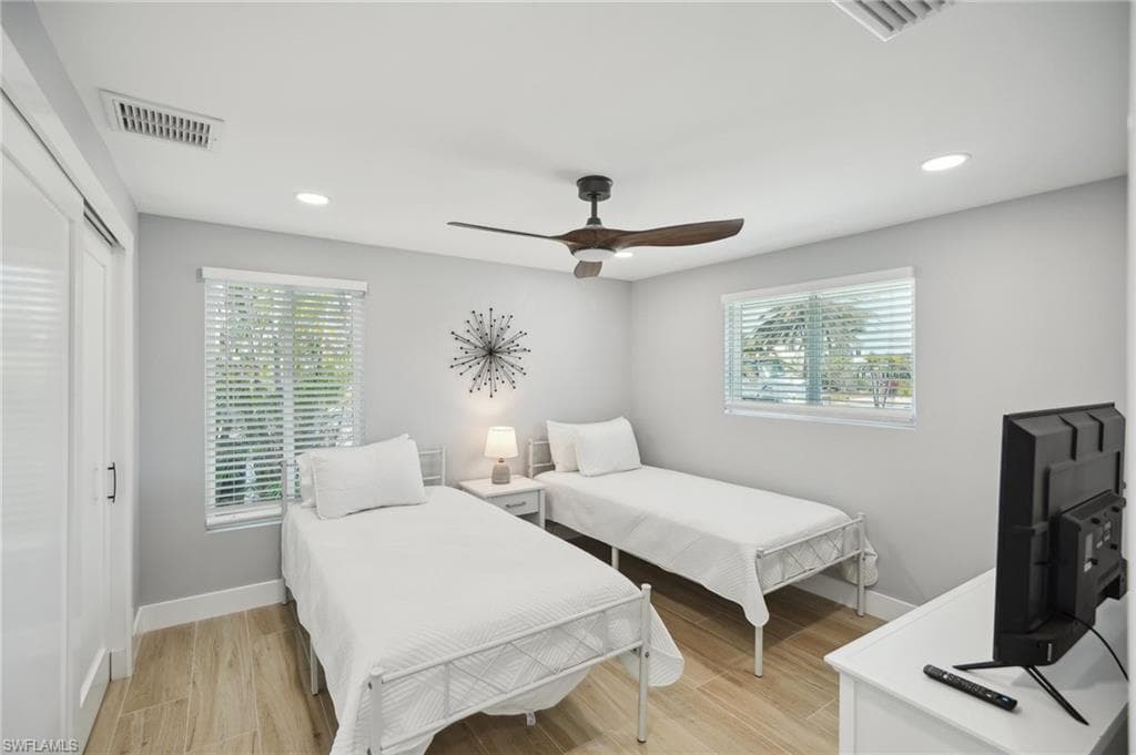 Bedroom with light wood-type flooring, multiple windows, recessed lighting, a ceiling fan, and a closet