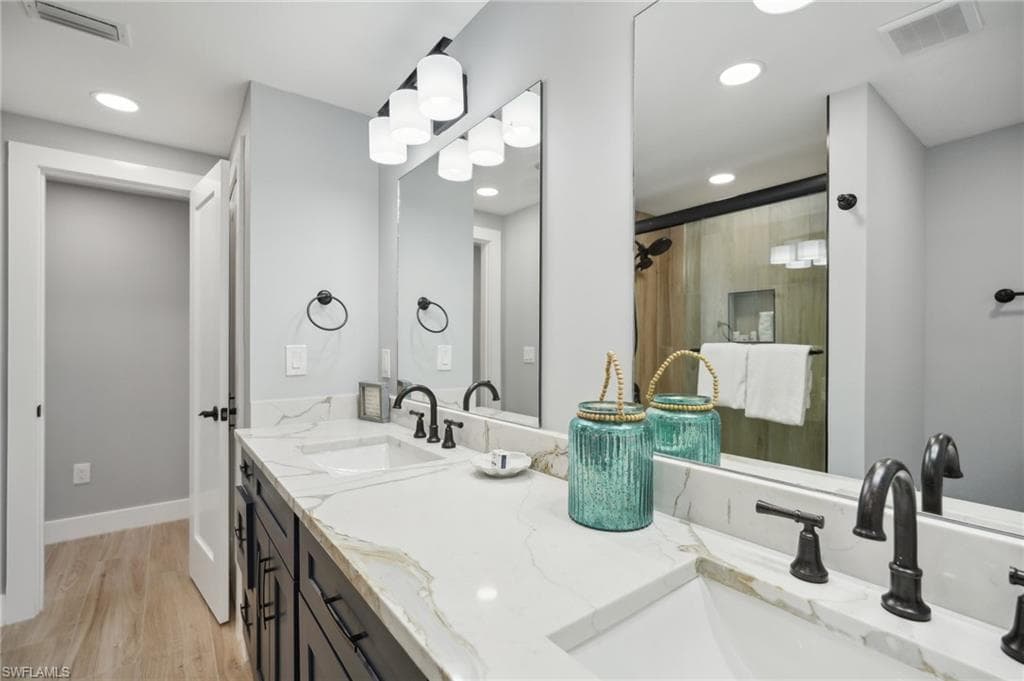 Full bathroom with light wood-style flooring, a shower stall, double vanity, and recessed lighting