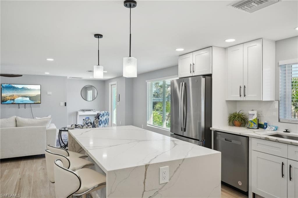 Kitchen featuring appliances with stainless steel finishes, light wood finished floors, plenty of natural light, light stone counters, and recessed lighting