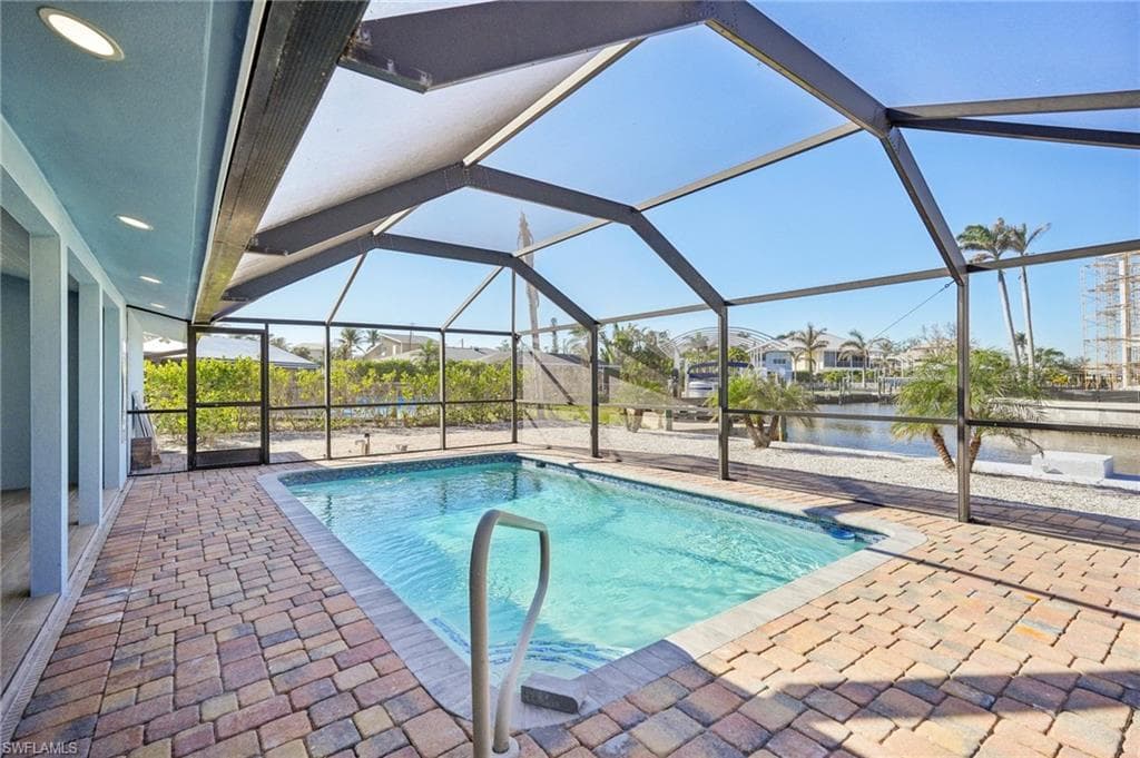 Outdoor pool featuring a sunroom, a patio area, a lanai, and a water view