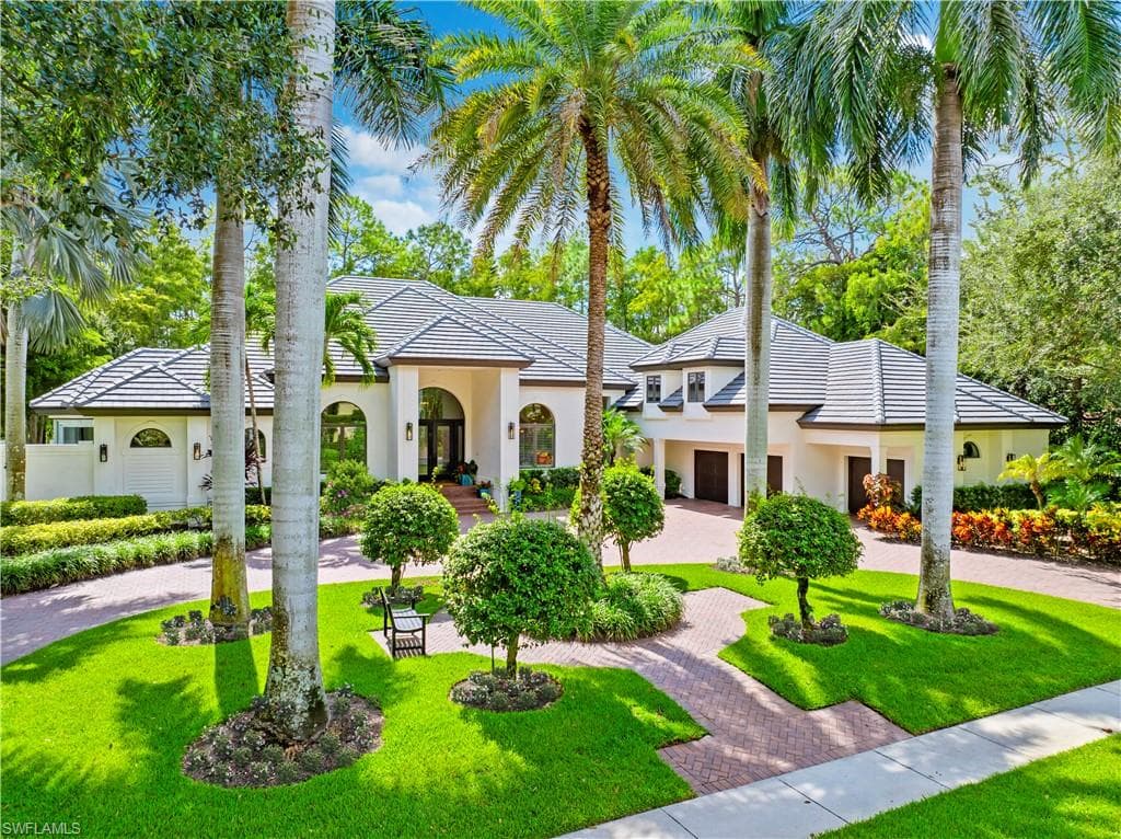 View of front facade with curved driveway, stucco siding, and a front lawn