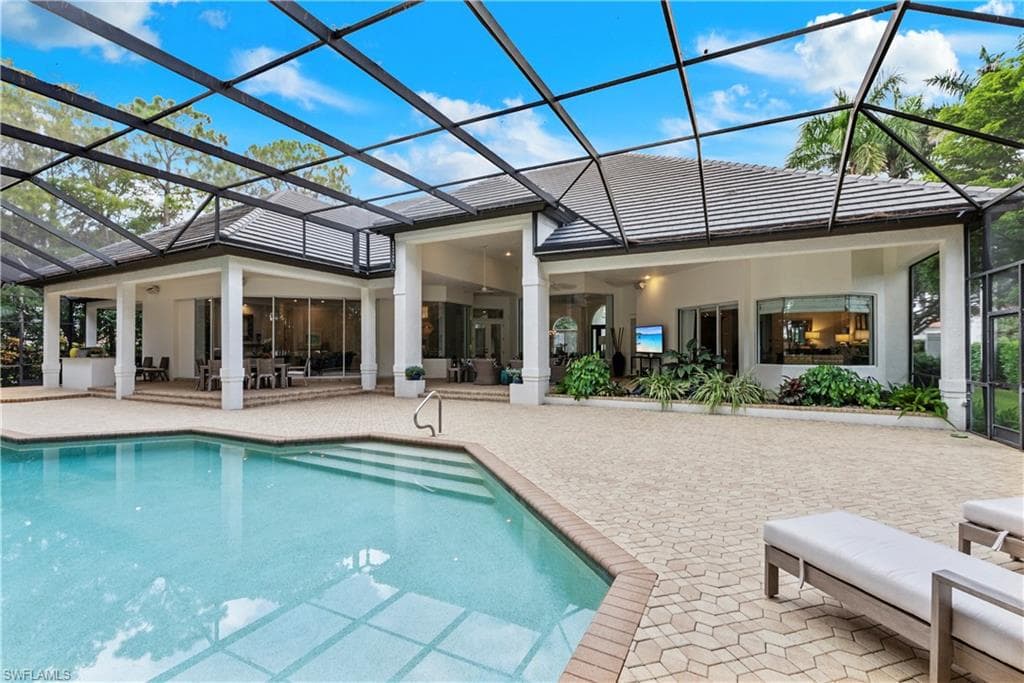 Rear view of house with a sunroom, glass enclosure, a patio area, an outdoor pool, and stucco siding