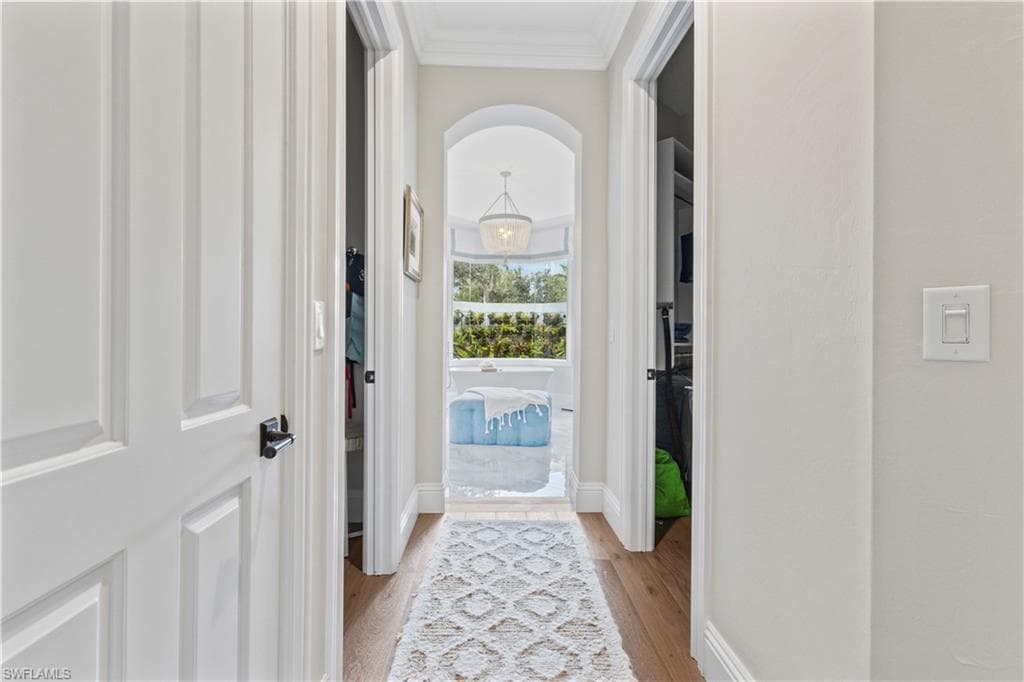 Doorway featuring wood finished floors, crown molding, and arched walkways