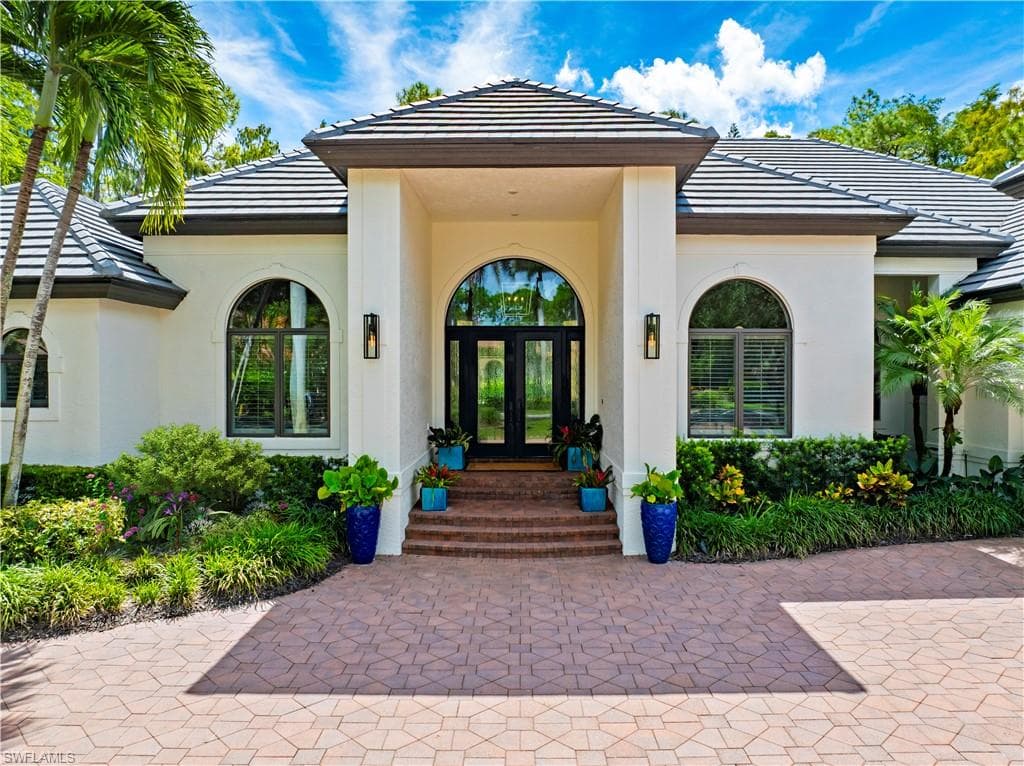 Property entrance with french doors, a tile roof, and stucco siding