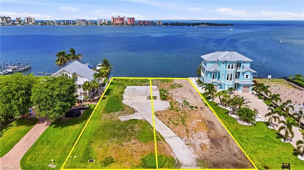 Expansive waterfront land parcel featuring a direct water frontage, concrete drive, and surrounding mature landscaping- Virtually Edited Image