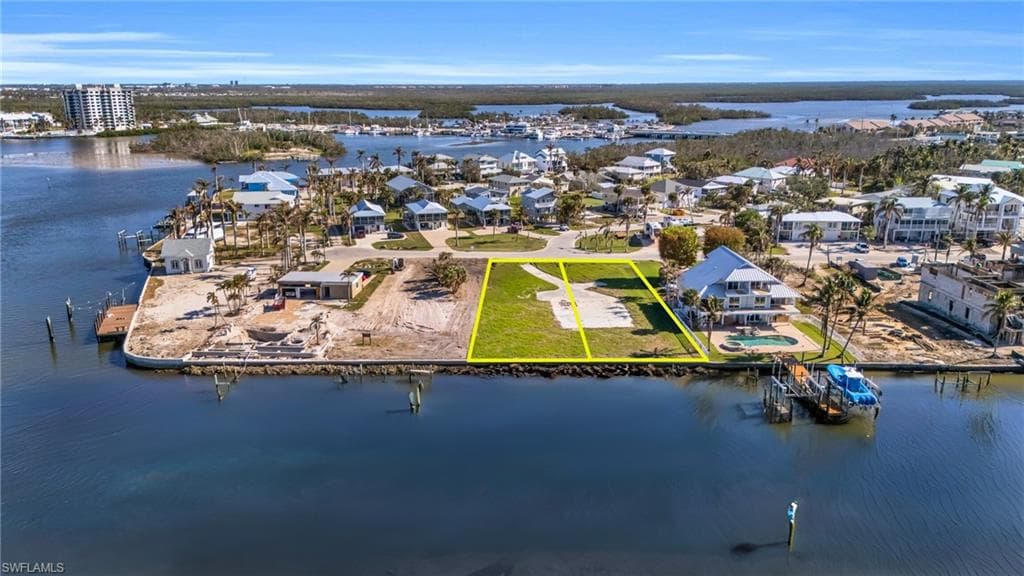 Aerial view of residential area featuring a large body of water and property parcel outlined - Virtually Edited Image