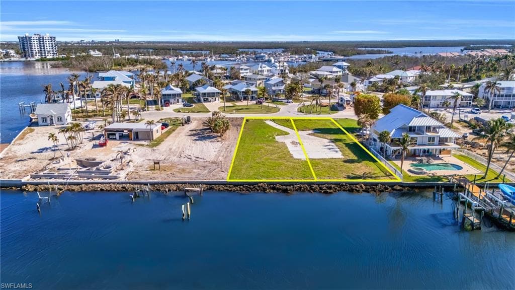 Aerial perspective of suburban area featuring a large body of water and property boundaries highlighted - Virtually Edited Image