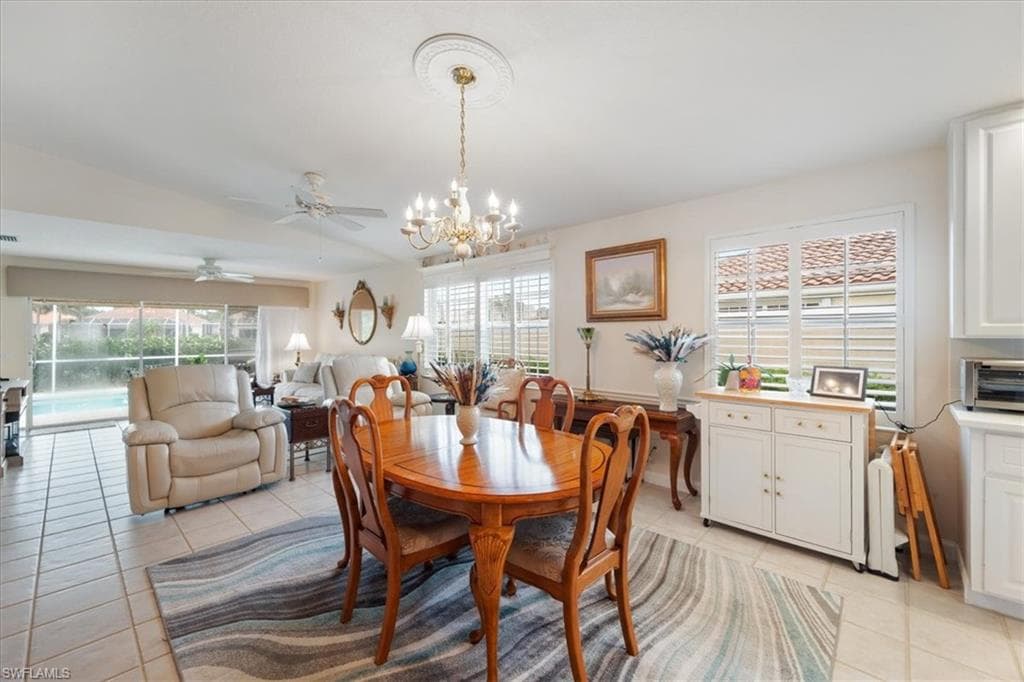 Dining area with light tile patterned floors, a chandelier, and a ceiling fan