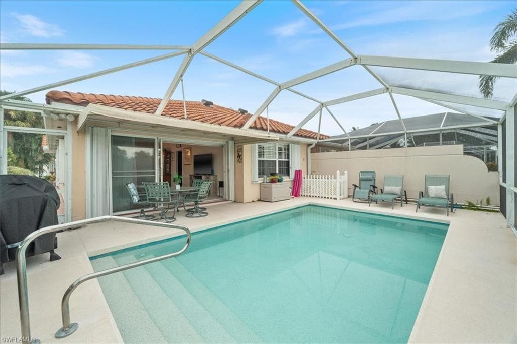 Rear view of property with a patio, a tile roof, a lanai, a sunroom, and an outdoor pool
