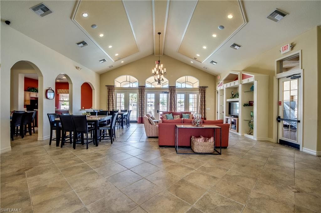 Clubhouse with high vaulted ceiling, a chandelier, arched walkways, recessed lighting, and french doors