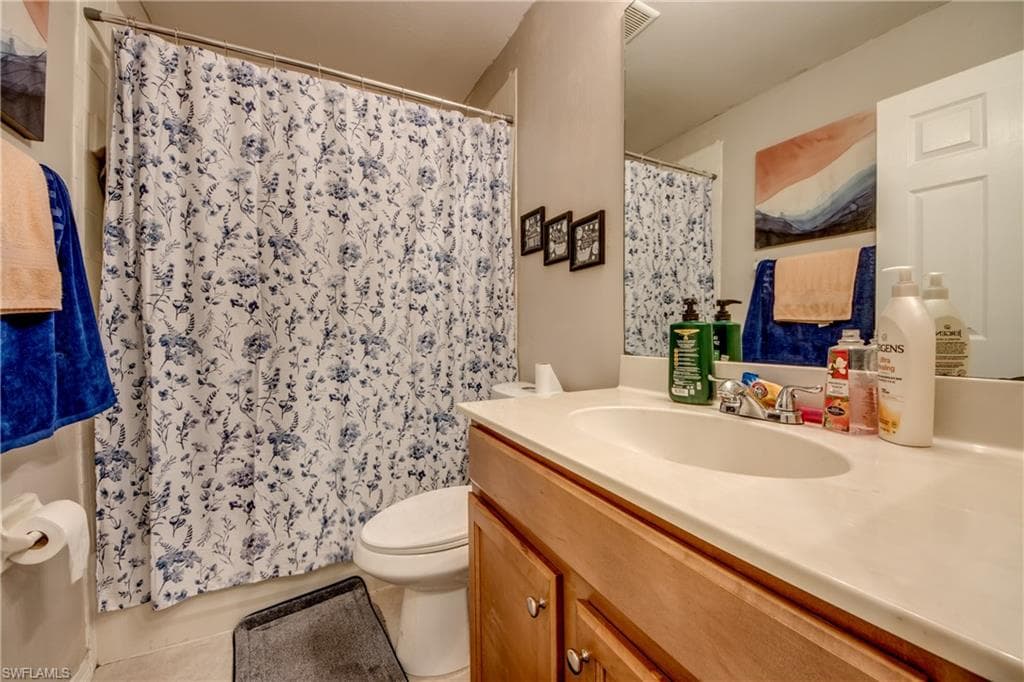 Full bathroom with vanity, light tile patterned floors, and a shower with shower curtain