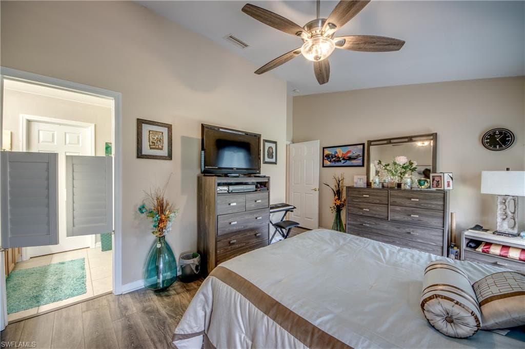 Bedroom with dark wood finished floors, vaulted ceiling, and ceiling fan