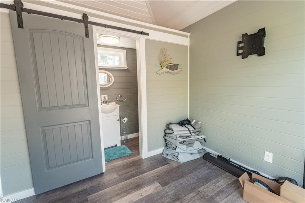 Mudroom with dark wood finished floors, wooden walls, and a barn door