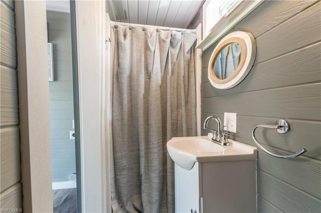 Full bathroom featuring vanity, curtained shower, and wooden walls