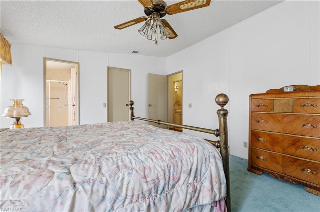 Carpeted bedroom featuring connected bathroom, a textured ceiling, and ceiling fan