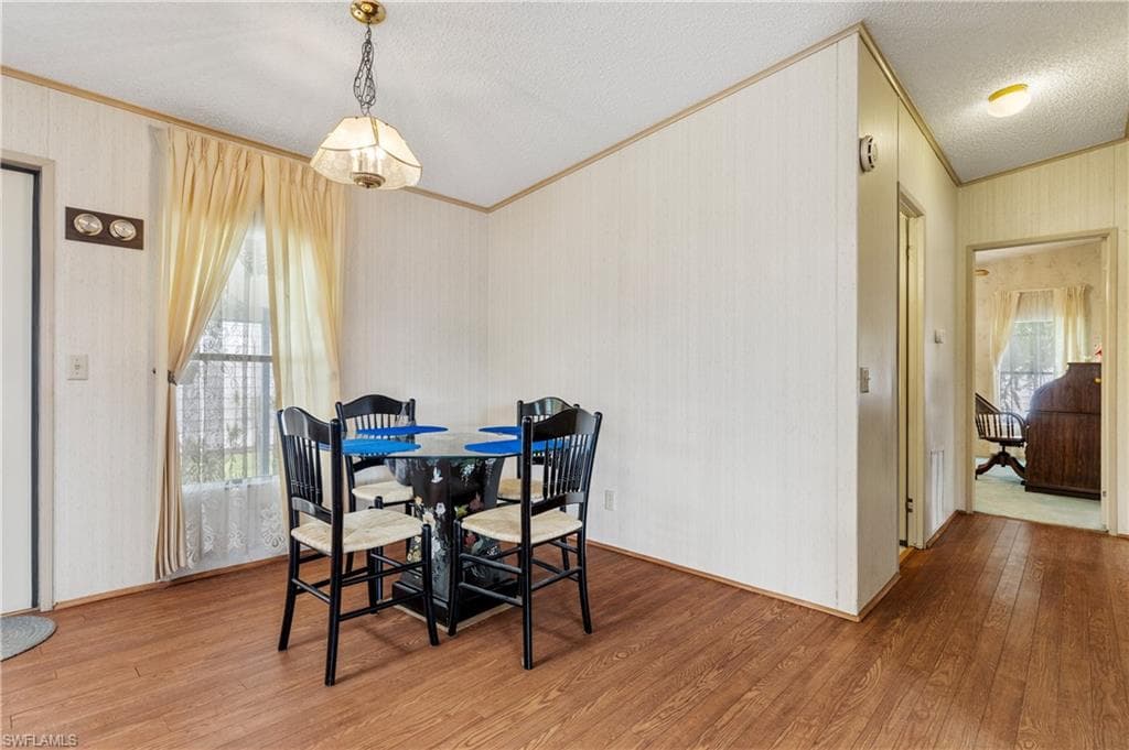 Dining area featuring light wood-style floors, plenty of natural light, crown molding, and a textured ceiling