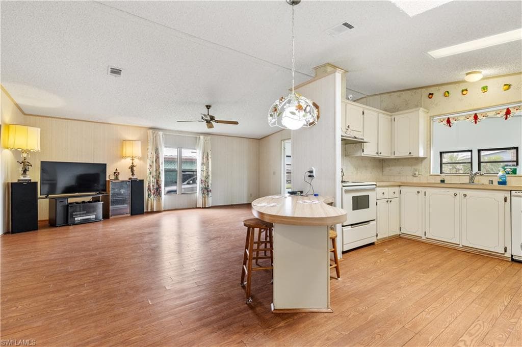 Kitchen with open floor plan, healthy amount of natural light, light countertops, hanging light fixtures, and a textured ceiling