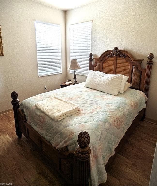 Bedroom featuring a textured wall and dark wood-type flooring