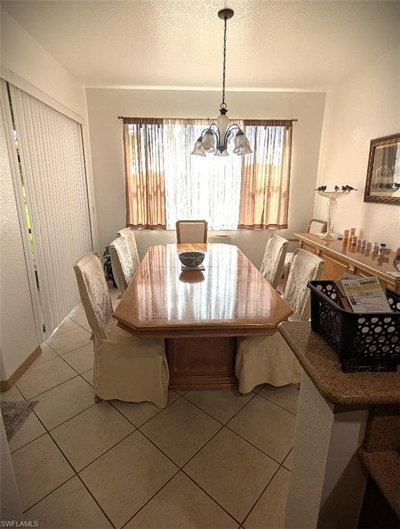 Dining area featuring light tile patterned floors, a textured ceiling, and a chandelier