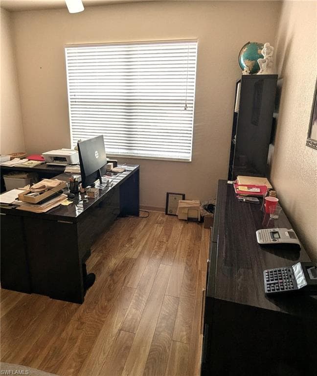 Home office with dark wood finished floors and baseboards