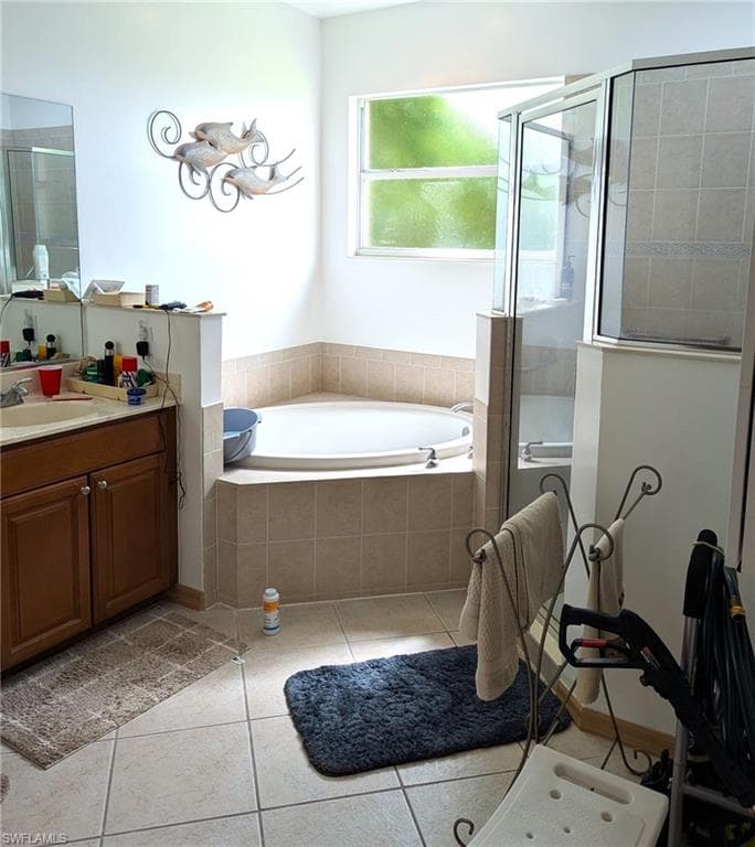 Full bath featuring a shower stall, vanity, a garden tub, and light tile patterned floors