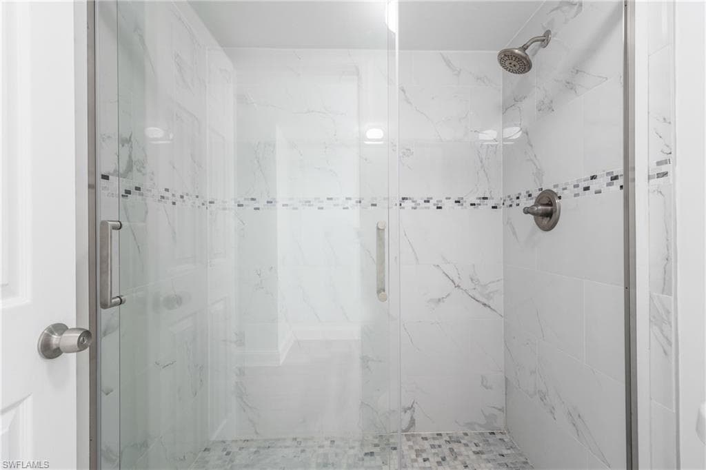 Full bath with a marble finish shower