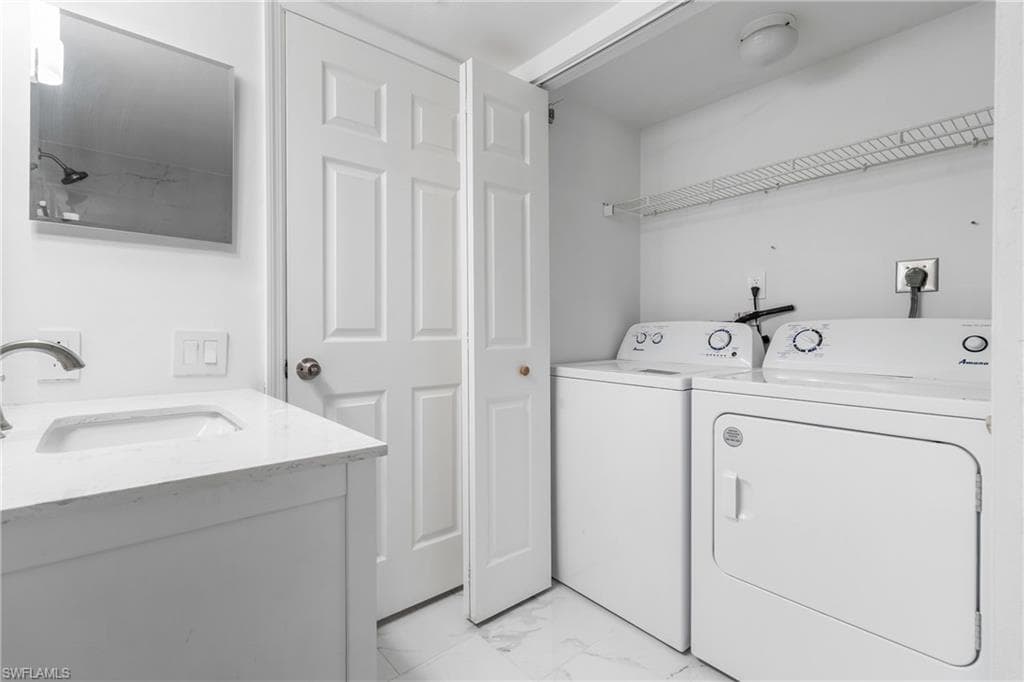 Washroom featuring light marble finish floors and washing machine and dryer
