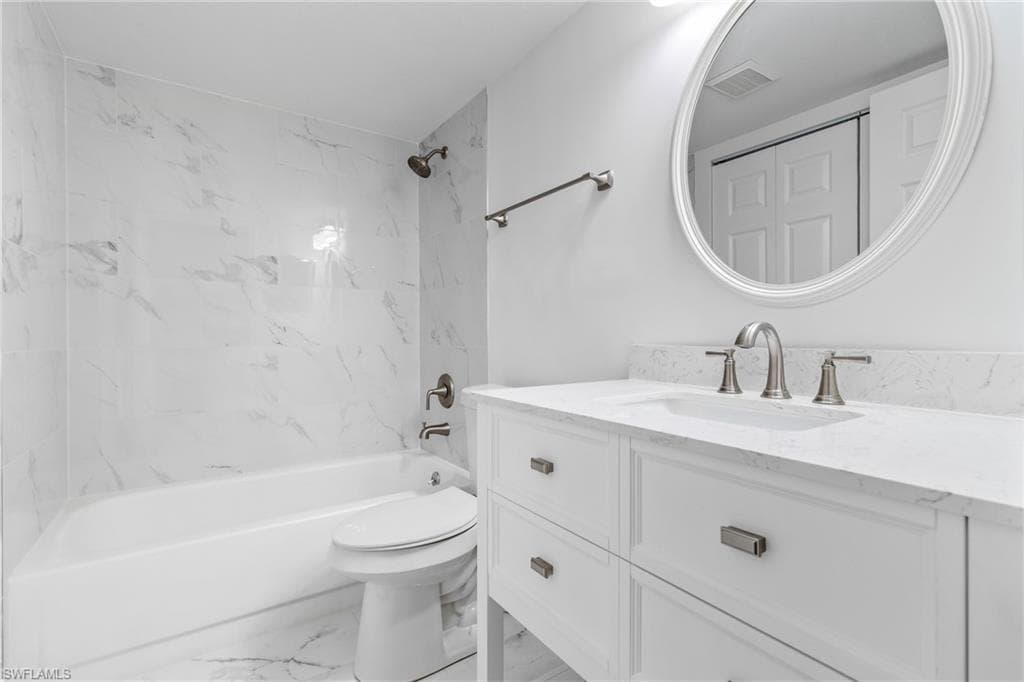 Bathroom featuring bathtub / shower combination, vanity, and light marble finish floors