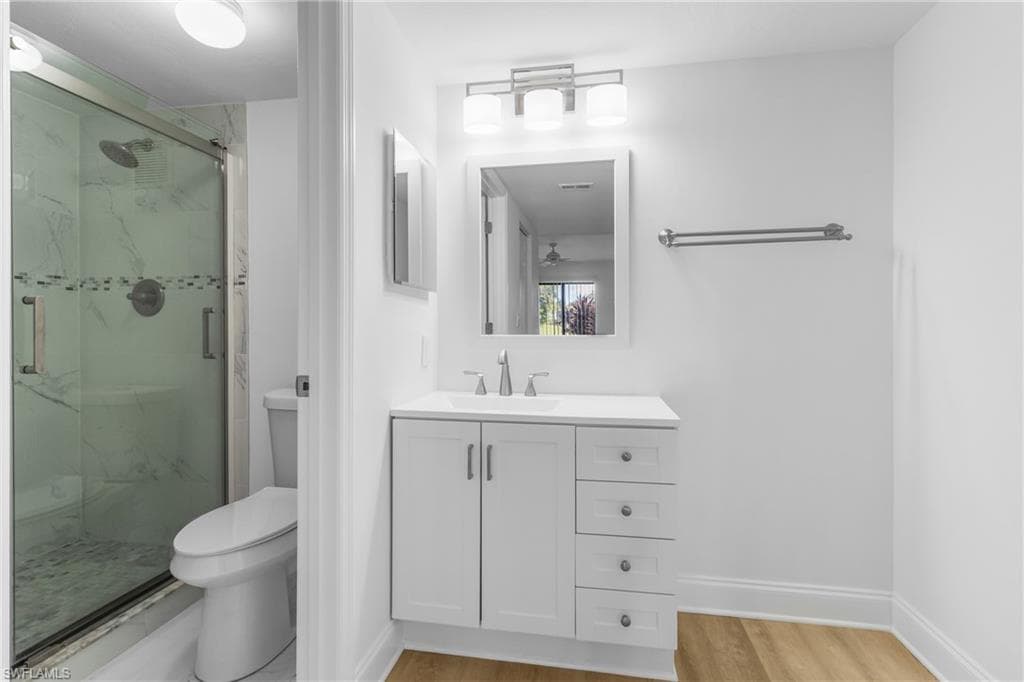 Bathroom featuring a marble finish shower, vanity, and light wood finished floors
