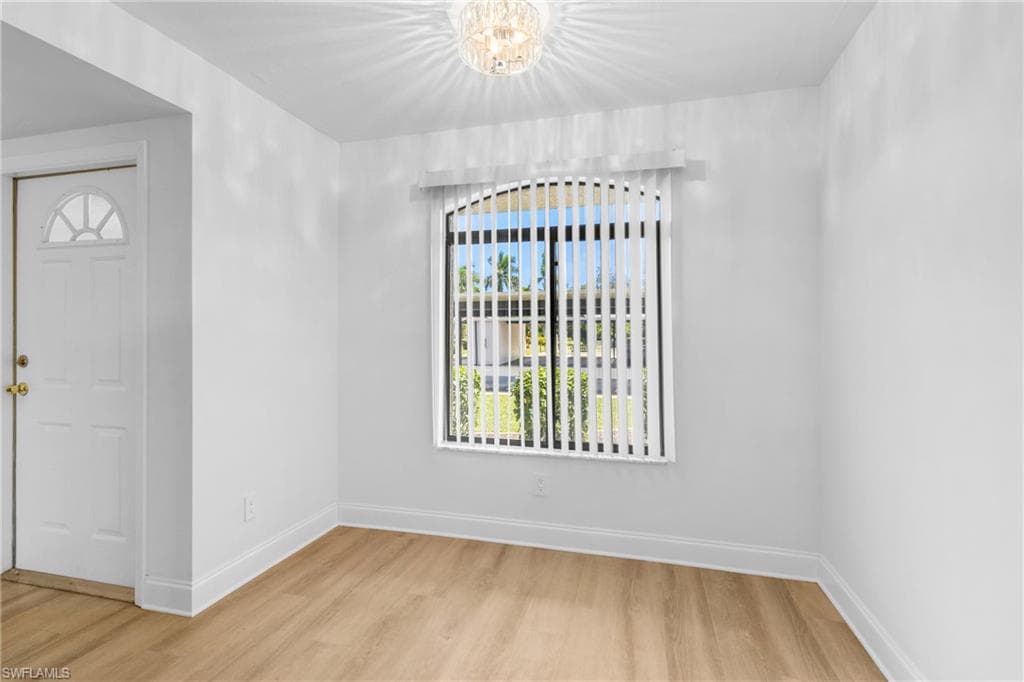 Empty room featuring light wood finished floors and a chandelier