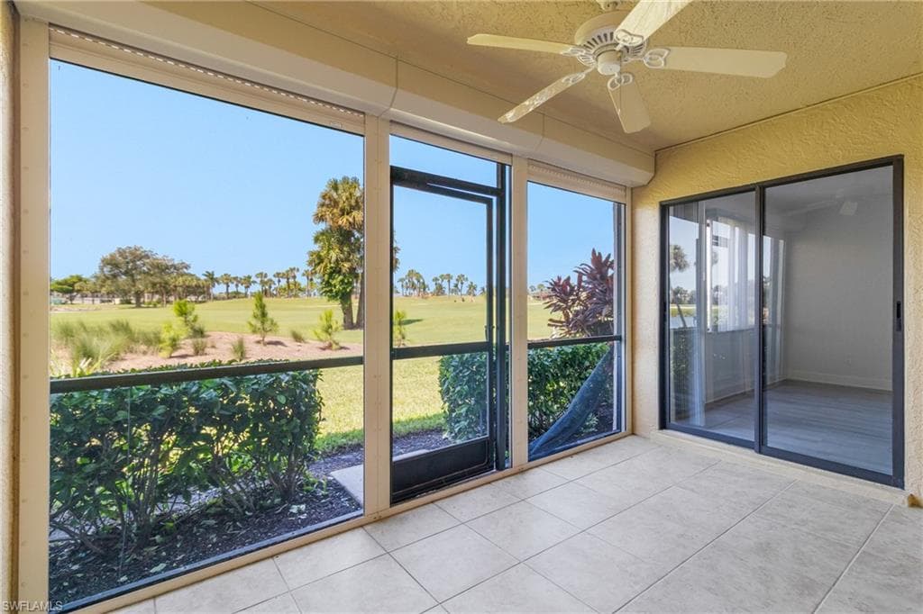 Unfurnished sunroom featuring ceiling fan and view of golf course